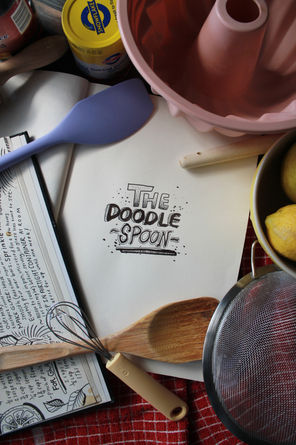 Kitchen utensils styled around a handwritten type design of the words "The Doodle Spoon"