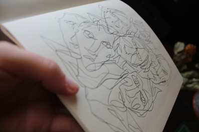 A pencil line drawing of many overlapping, abstract faces