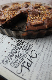 Beautiful home styling of a homemade chocolate snickers tart and handwritten recipe