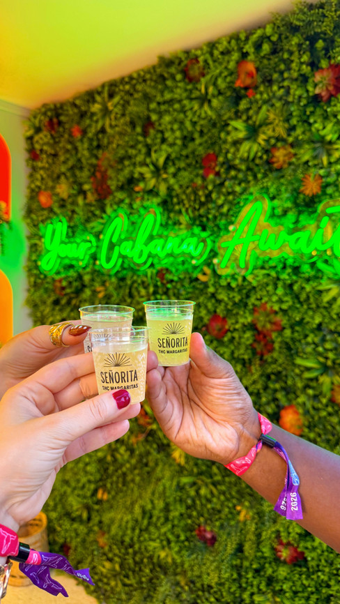 Señorita THC Margaritas drink samples at Country Thunder Florida with a vibrant floral backdrop and neon sign.