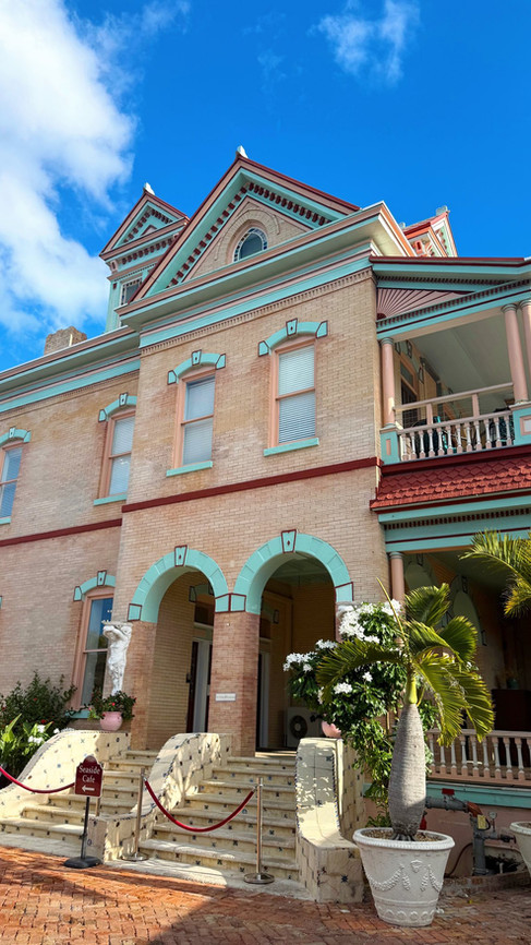 Historic pastel colored home near the Southernmost Point in Key West with ornate balconies and tropical landscaping.
