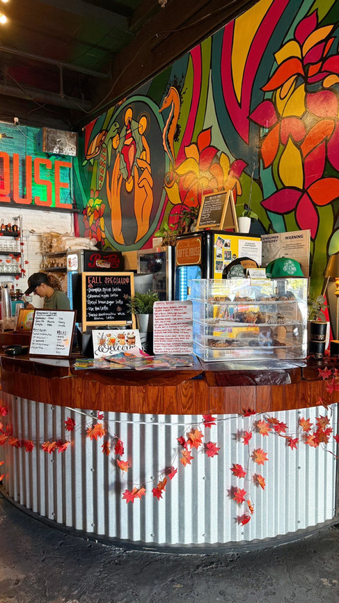Bright and colorful counter area inside The Koffie House café in Key West with tropical murals and pastries on display.