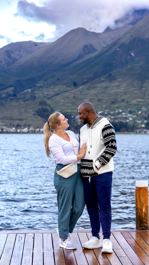 Couple standing on a dock at a Lake in Ecuador with mountain views in the background, sharing a romantic travel moment during Day 2 of their Ecuador trip.