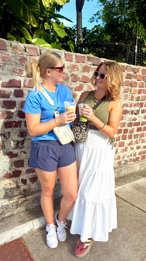 Two women holding iced drinks while walking through a sunny street in Key West, Florida.