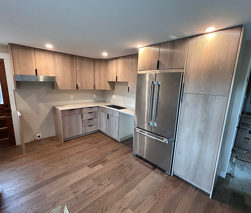 A newly remodeled kitchen of with brown hardwood floors and modern cabinets