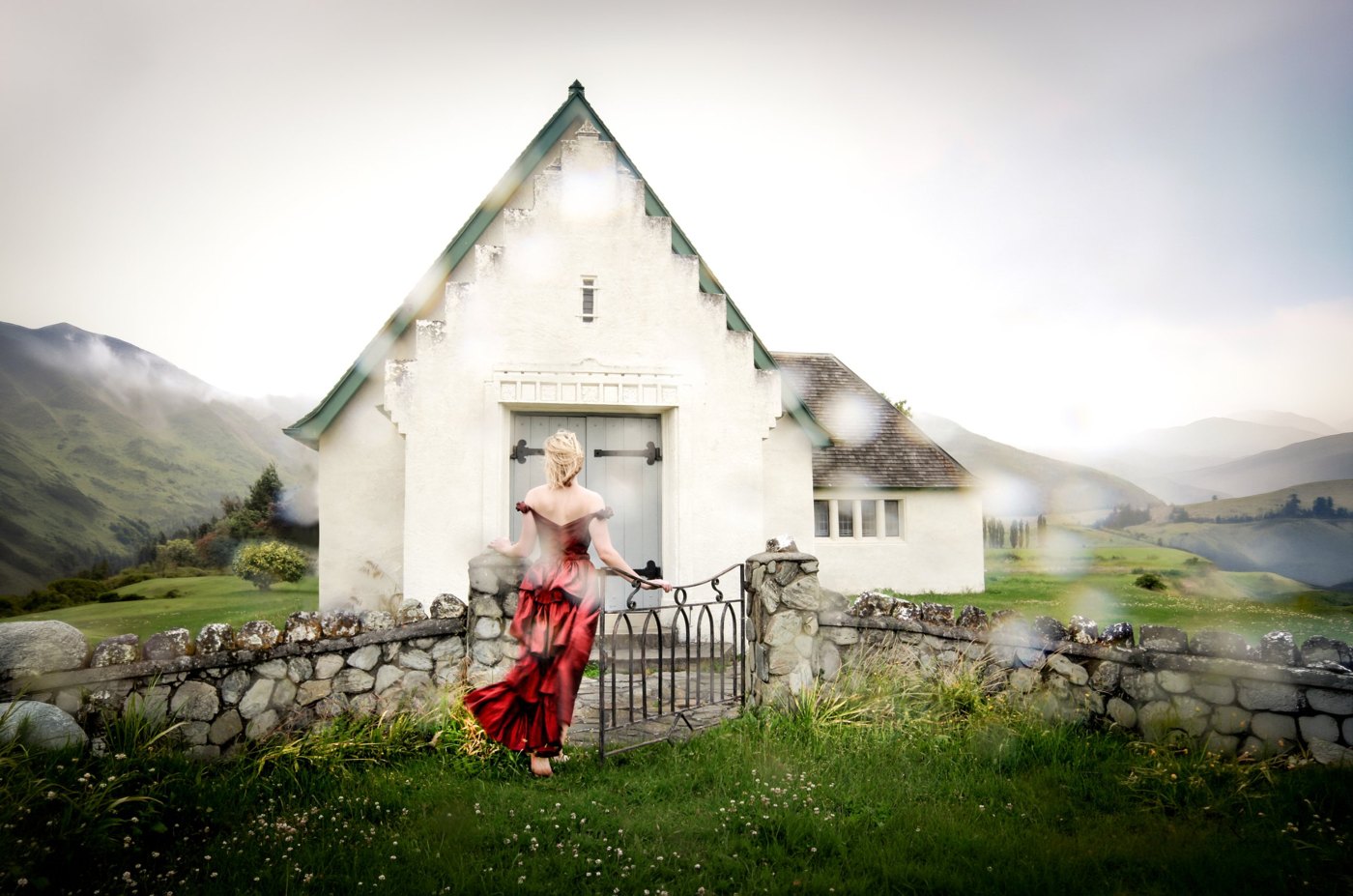 A woman in a red dress at the gate of a white chapel