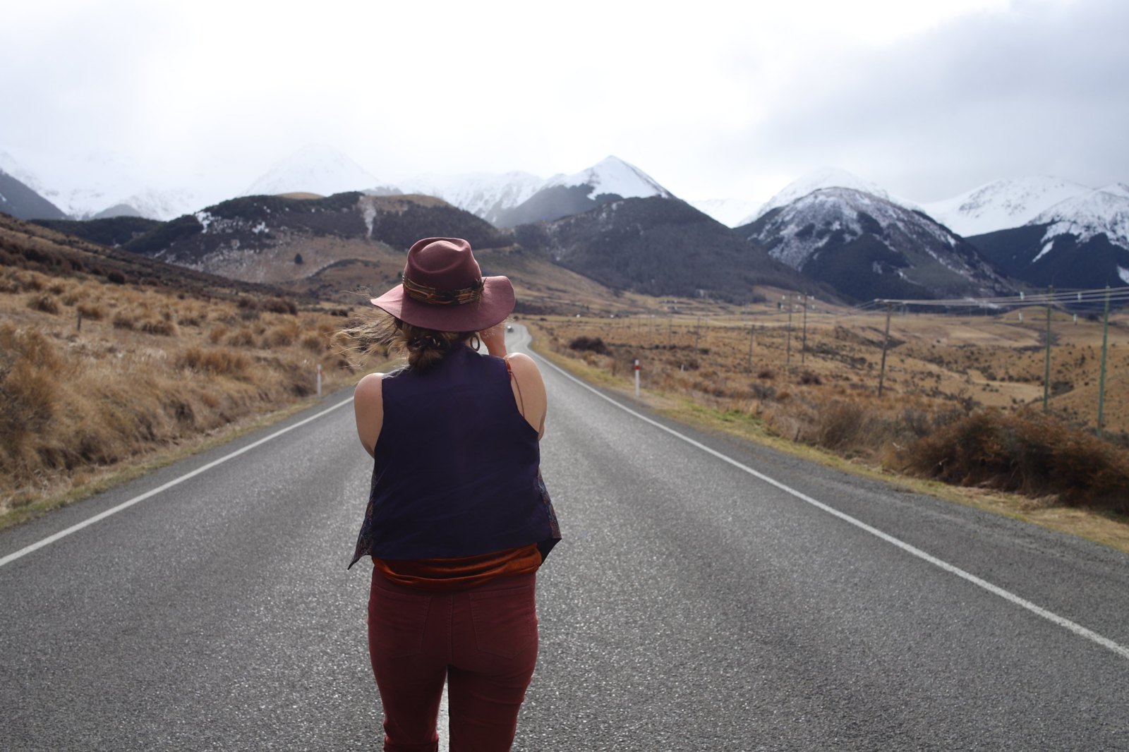Shannon on an open road towards snowy mountains