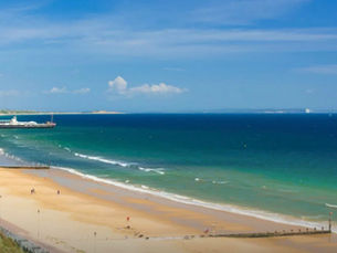 A woman has been sexually assaulted while with her family at a beach – with a man arrested.