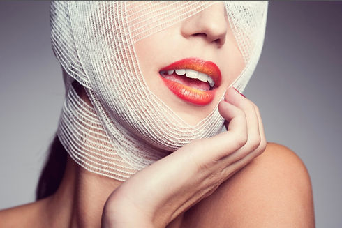 Close-up of a woman’s face with red and orange ombre lipstick, wrapped in medical gauze, conveying luxury and care—ideal for Opulent Concierge Nursing, specializing in in-home, post-operative care for plastic surgery patients