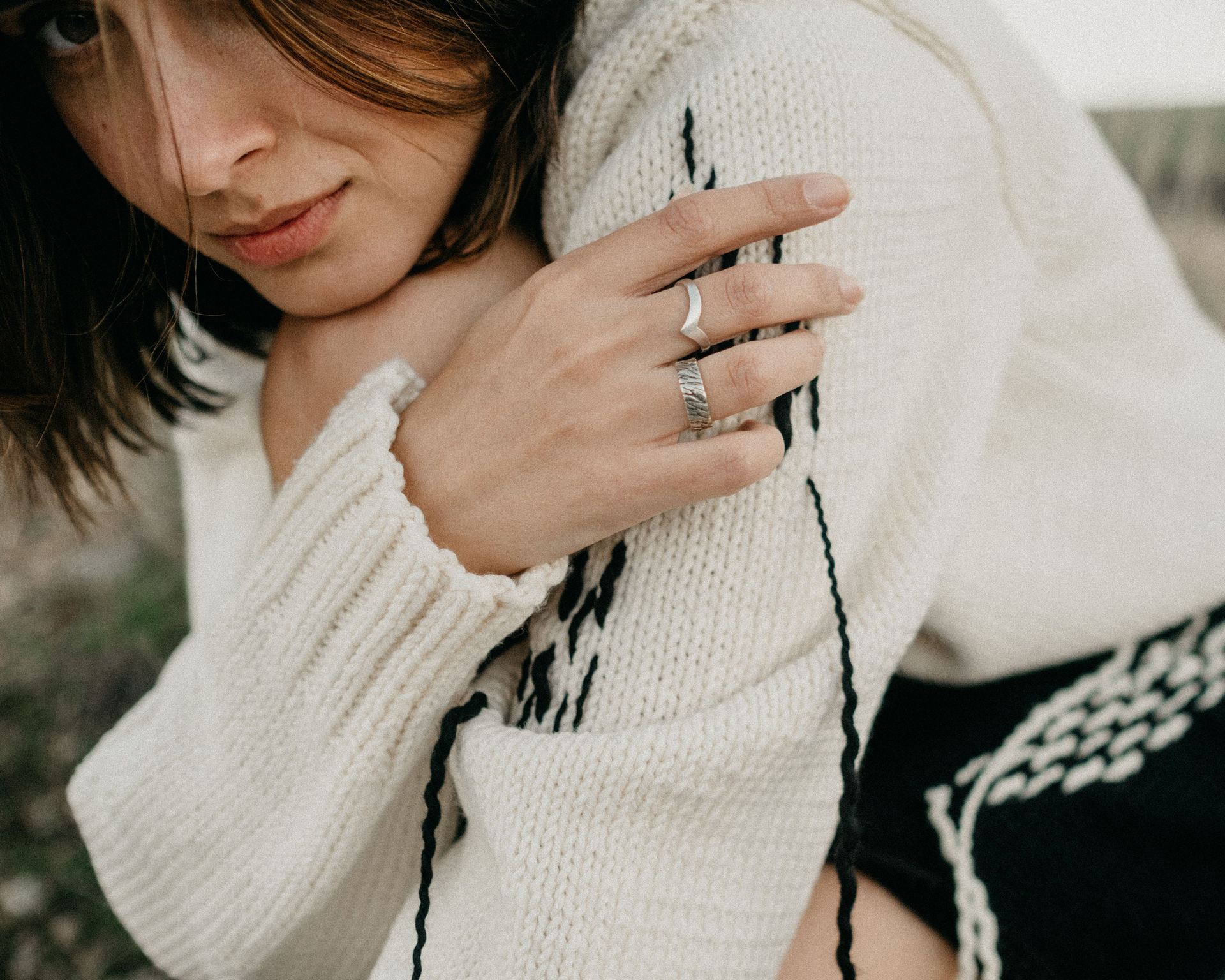 Detail shot of a white ribbed merino wool sweater sleeve with black stitch accents.