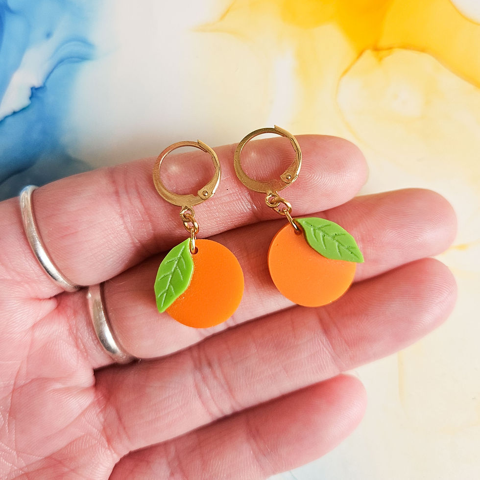 Thumbnail: Handmade whimsical orange resin charms on golden huggie hoops