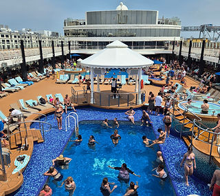 Outdoor pool deck on the Norwegian Gem cruise ship during the Boston to Bermuda route, with guests swimming and relaxing.