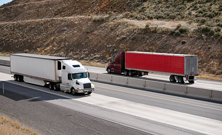 2 Long Haul Trucks Driving past each other on highway with containers
