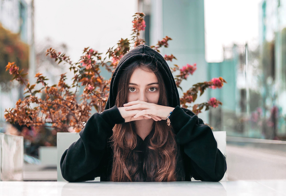 Pretty young brunette woman wearing black hoodie.