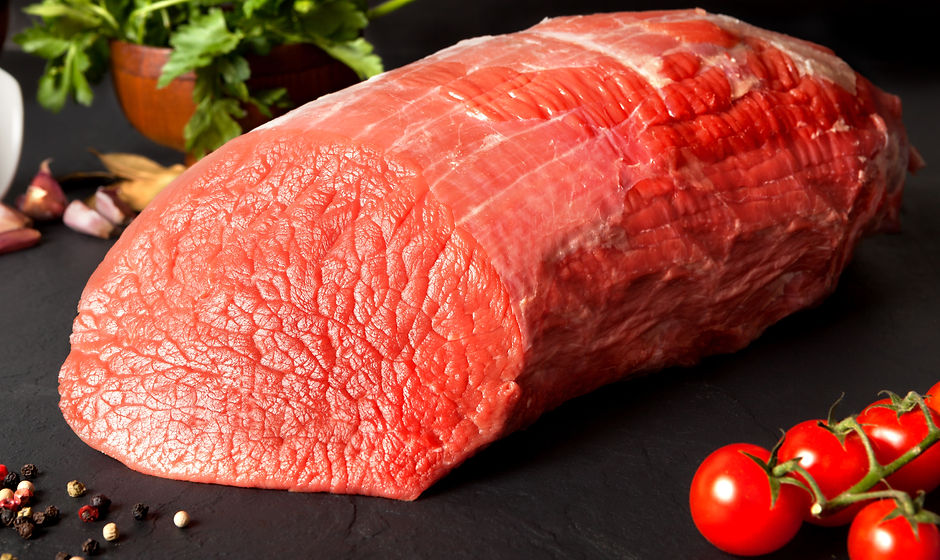 Still life raw beef round over black gro