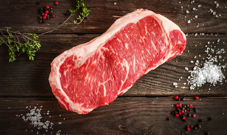 raw strip loin steak on white wooden bac