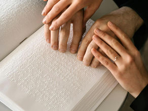 dos manos asisten a la lectura en braille