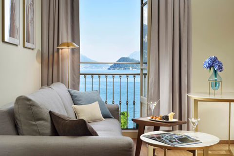 Junior suite with balcony and lake view at a Lake Como hotel, featuring a cosy seating area and soft decor.