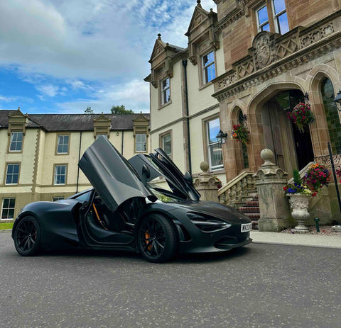 McLaren 720S parked outside a grand Loch Lomond hotel, combining Scottish lakeside luxury with supercar style.