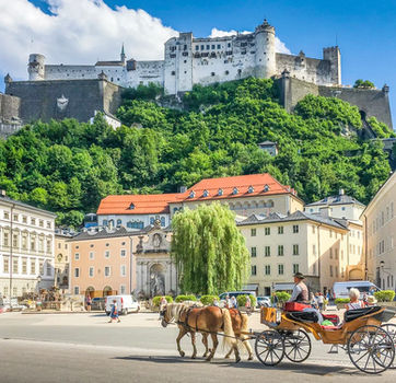 Historic centre of Salzburg with Hohensalzburg Fortress and a horse-drawn carriage, featured stop on the German Alpine Road and autobahn tour.