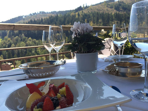 Gourmet dessert and wine served on a terrace overlooking Black Forest hills at a fine-dining restaurant.