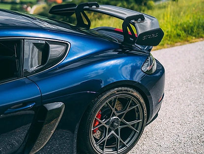 wing of Porsche 718 Cayman GT4 RS on top of scenic alpine road
