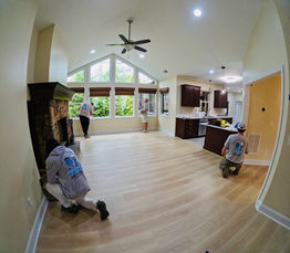Interior painters applying fresh paint to walls and trim in the living room of a home