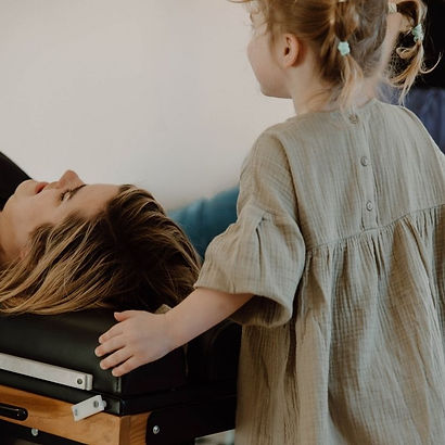 Mom receiving chiropractic adjustment while daughter watches at Soma Chiropractic in Delray Beach