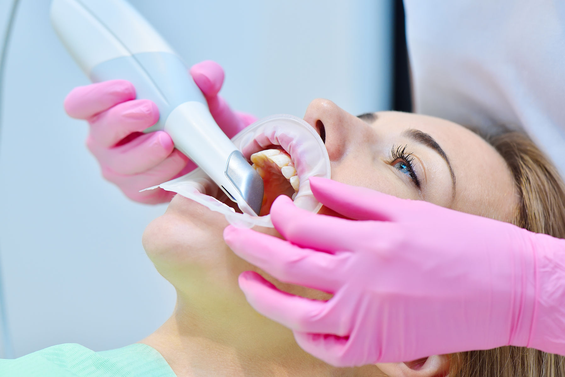 Woman dentist using dental intraoral scanner while examining patient teeth in dental clini
