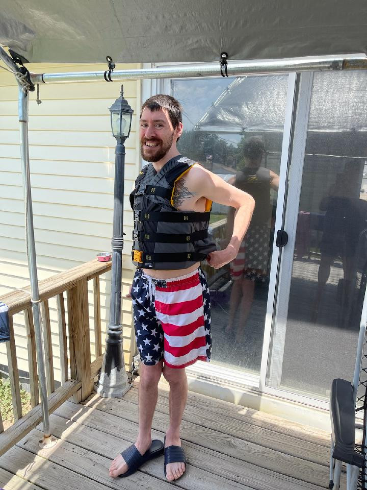 tyson on back porch with usa flag swimming shorts and vest
