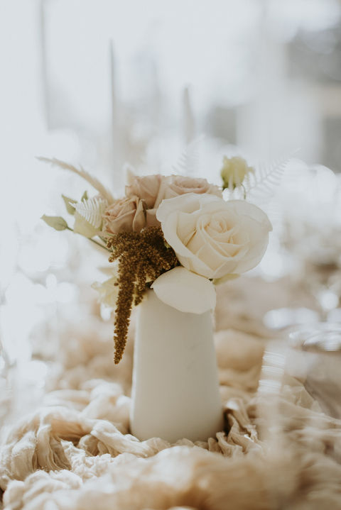 White vase with flowers on a table, soft focus and neutral colors