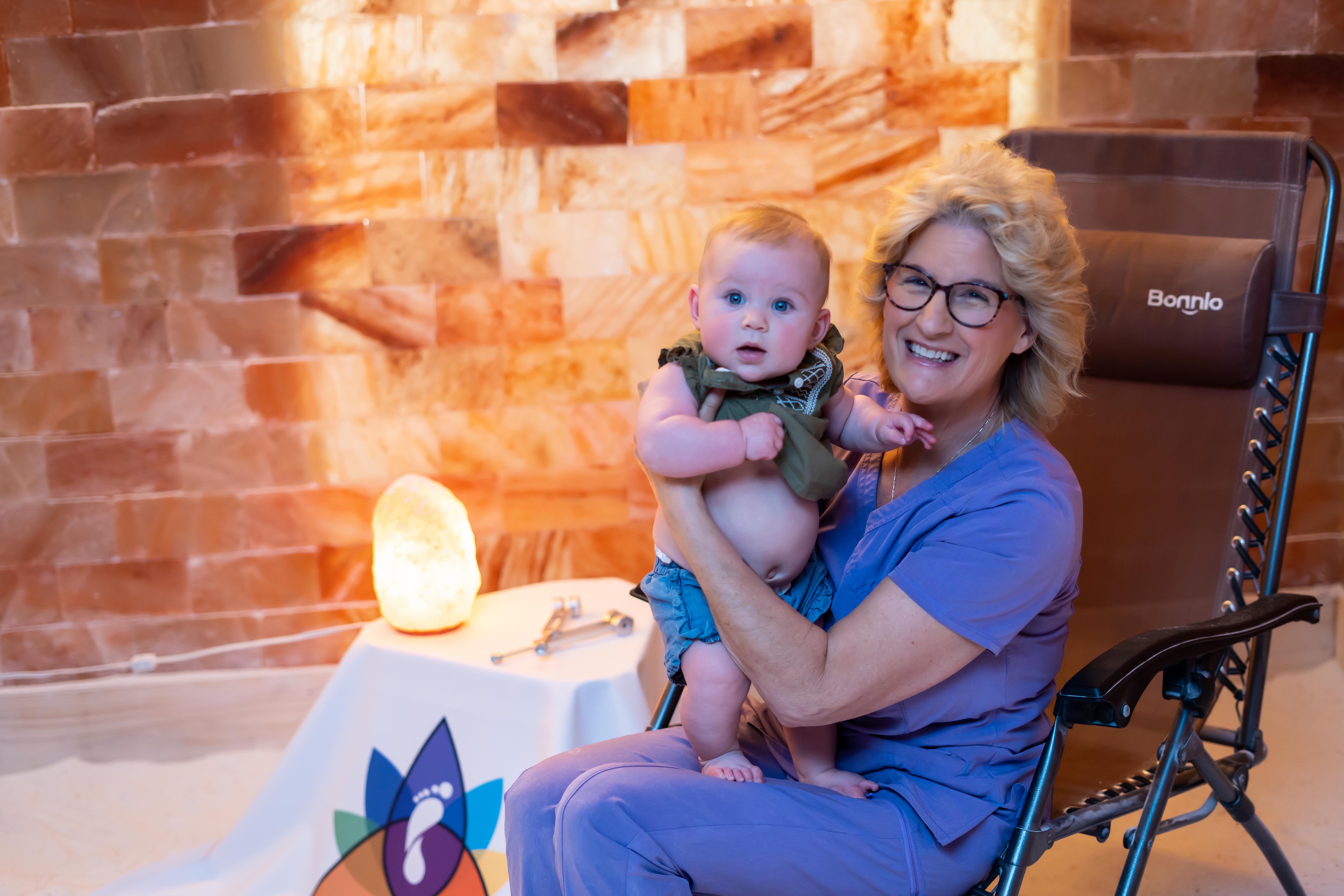 Woman holding a baby in a salt therapy room.