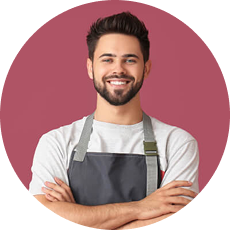Smiling man wearing apron in a beverage shop looking at the camera.