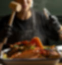 A woman holding a hammer over a large seafood boil at Gothic Crab in Brighton