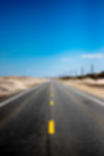A roadway bordered by sand on both sides