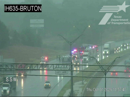 TxDOT traffic camera view of northbound I-635 at Bruton Road showing an overturned white SUV and emergency responders on wet pavement Thursday midday