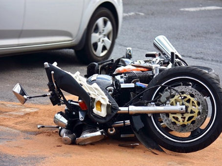 Illustrative stock photo of a damaged motorcycle lying on a roadway next to a car; not a photo of the FM 920 crash