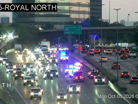 TxDOT traffic camera view of southbound US 75 near Royal Lane in Dallas showing emergency vehicles with lights on and backed-up traffic Monday morning