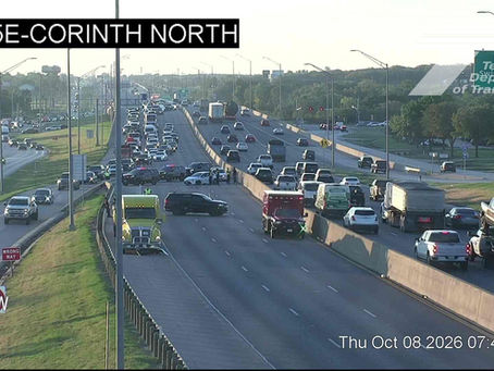 TxDOT traffic camera view of I-35E at Corinth North showing emergency vehicles, a tow truck and people on the closed northbound lanes Thursday morning