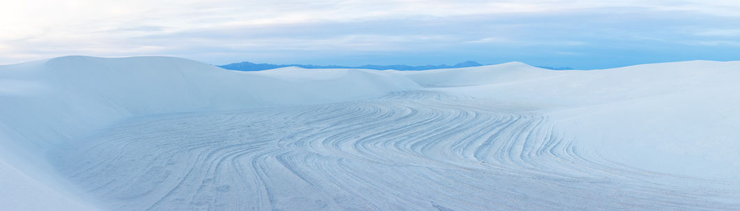 Grooves in a valley of white sand dunes on an overcast morning.