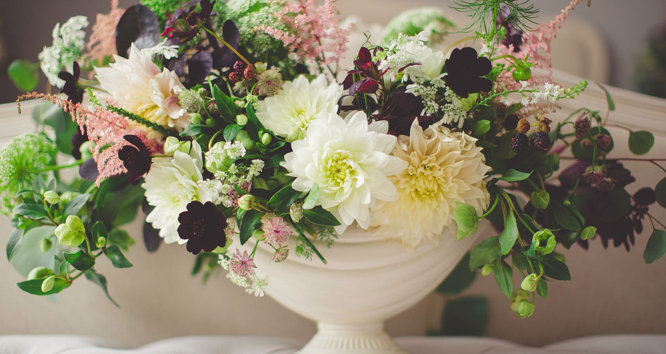 Blumenarrangement in weißer Vase.