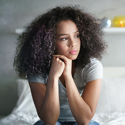 Lonely young latina woman sitting on bed