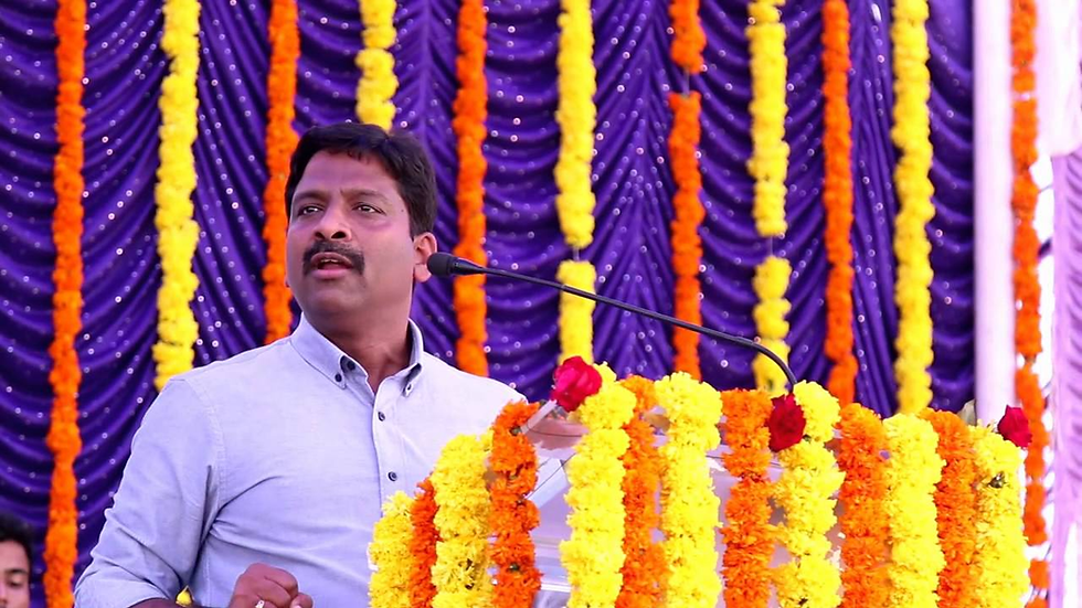Es. Chakravarthy speaking at a podium with a microphone, showcasing strong leadership presence in a formal event setting.