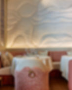 Soft architectural lighting illuminating 3D textured wall panels at Suelo Paris dining area.