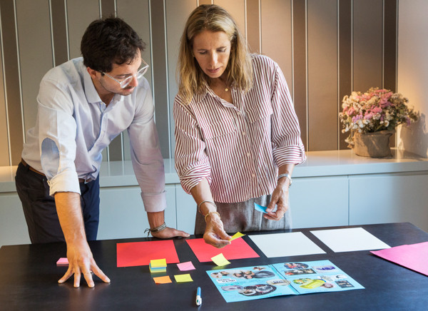 Dinámica de coaching con dos personas sentadas, una mesa y papeles de trabajo