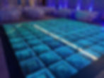 Modern LED infinity mirror dance floor with glowing teal lights, providing a futuristic 3D effect for a party or reception.
