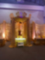 A stage with a throne on it for a themed event with gold curtains draped around it.