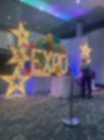 The entrance of an event with giant LED stars and letters that spell "EXPO".