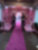 Entrance to a themed party with two greeters dressed up in uniform with a pink carpet leading to the door.
