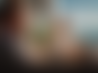 Hotel executive sitting on a sunny resort terrace reviewing information on a smartphone, with the ocean and hotel guests in the background.